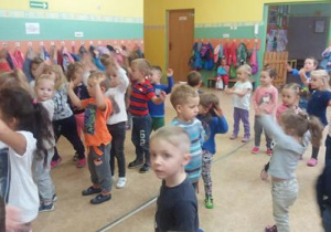 Stojące dzieci unoszą ręce w górę.